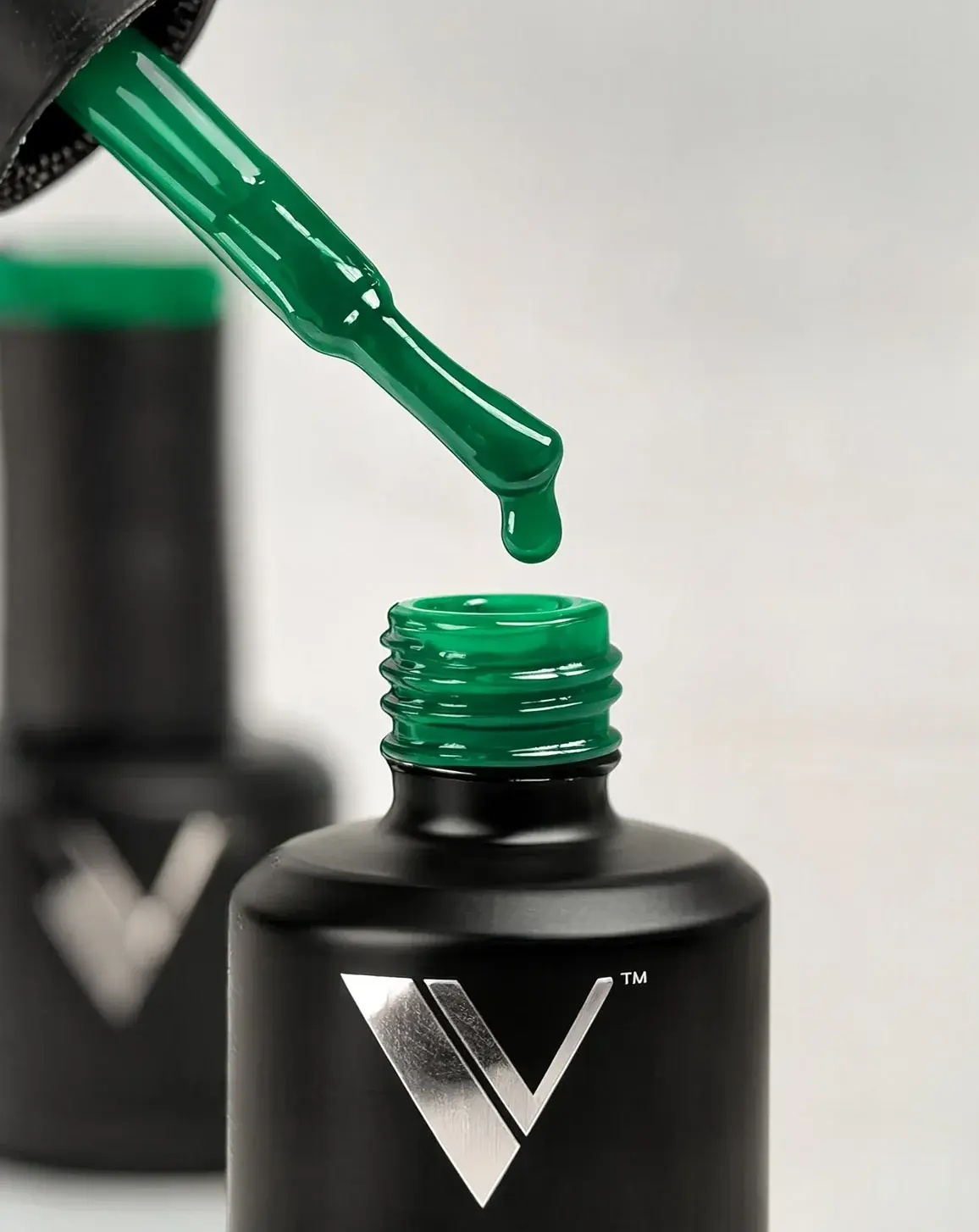 Esmalte en gel verde cayendo del pincel sobre el frasco