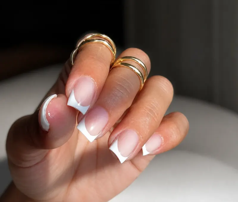 Uñas con francesa blanca y anillos dorados